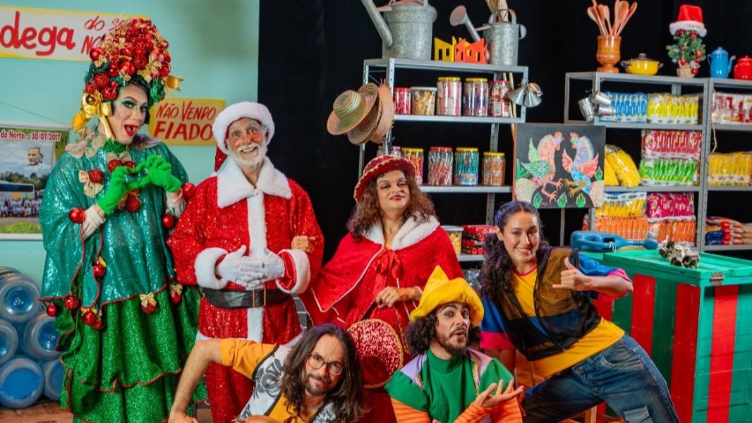 pessoas fantasiadas de personagens natalinos posam para a foto em um cenário